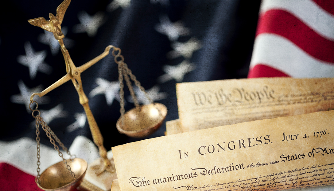 Photo of US flag of Original 13 Colonies with legal scales and visible headers of US Constitution and Declaration of Independence.